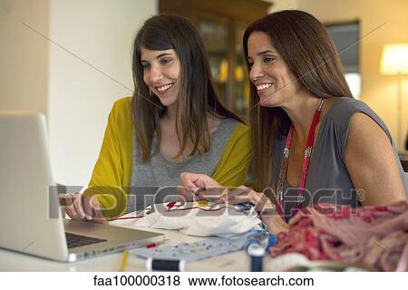 Stock Photo - Sisters learning embroidery together by watching online videos. Fotosearch