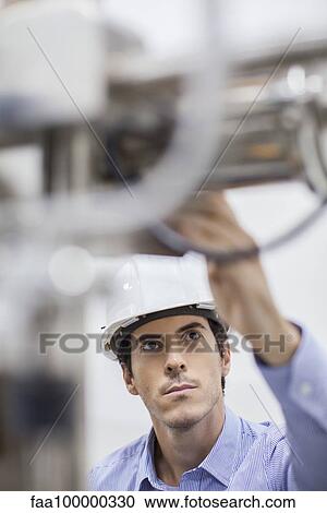 Stock Image - Technician checking industrial plant equipment. Fotosearch