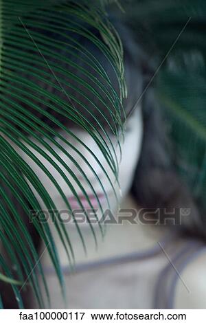 Stock Photo - Woman hiding behind palm leaf. Fotosearch