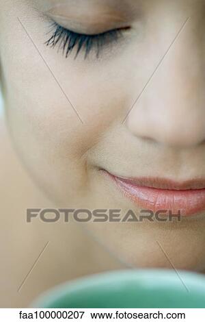Stock Photo - Woman smelling hot drink, eyes closed. Fotosearch