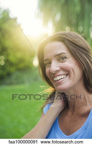 Stock Image - Woman smiling outdoors, portrait. Fotosearch