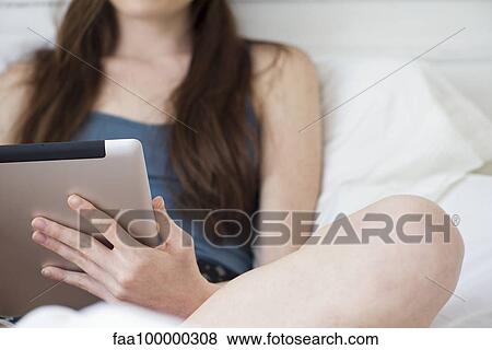 Stock Photo - Woman using digital tablet in bed. Fotosearch