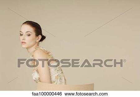 Stock Photograph - Woman wearing ruffly dress, looking away sadly, portrait. Fotosearch
