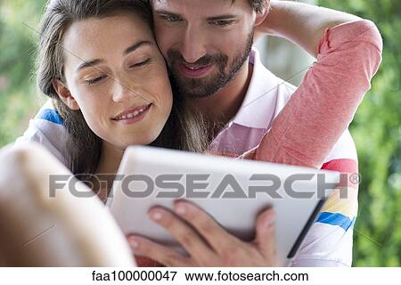 Stock Photo - Young couple using digital tablet together outdoors. Fotosearch