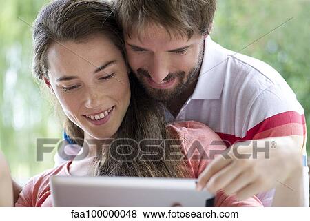 Young couple using digital tablet together outdoors View Large Photo Image Stock Photo - Young couple using digital tablet together outdoors. Fotosearch