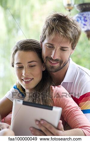 Stock Photo - Young couple using digital tablet together outdoors. Fotosearch