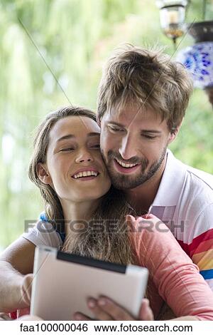 Stock Photograph - Young couple using digital tablet together outdoors. Fotosearch