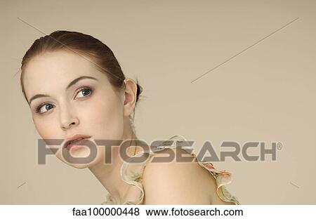 Stock Photo - Young woman looking away in thought, portrait. Fotosearch