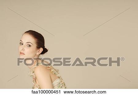 Stock Image - Young woman looking over shoulder sadly, portrait. Fotosearch
