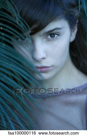 Young woman looking through palm leaf, portrait View Large Photo Image Stock Photograph - Young woman looking through palm leaf, portrait. Fotosearch