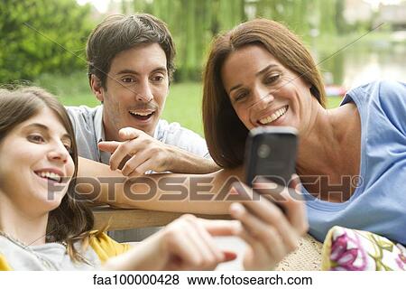 Stock Photo - Young woman sharing photos on smartphone with friends. Fotosearch
