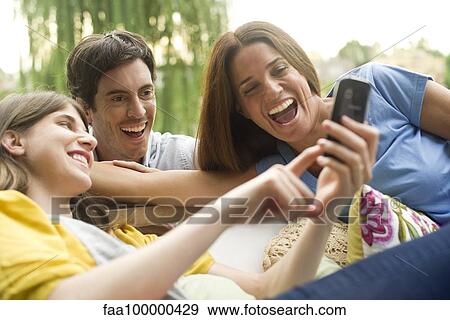 Stock Photo - Young woman sharing photos on smartphone with friends. Fotosearch