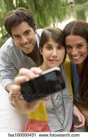 Stock Image - Young woman taking selfie with parents. Fotosearch