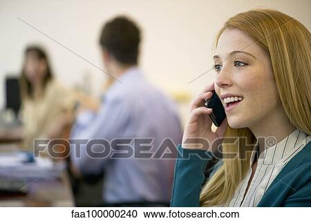 Young woman talking on cell phone in office View Large Photo Image Stock Image - Young woman talking on cell phone in office. Fotosearch