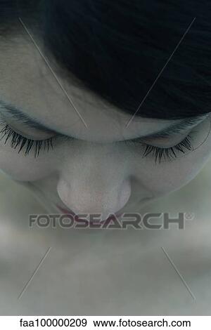 Stock Photo - Young woman with head down and eyes closed, close-up. Fotosearch
