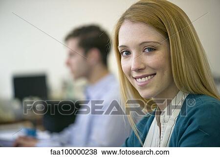 Stock Photo - Young woman working in office, smiling cheerfully. Fotosearch