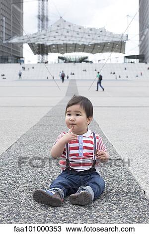 Baby boy sitting on the ground in city square View Large Photo Image Stock Image - Baby boy sitting on the ground in city square. Fotosearch