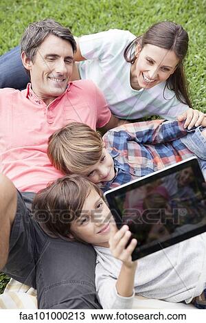 Boy photographing family with digital tablet camera View Large Photo Image Stock Image - Boy photographing family with digital tablet camera. Fotosearch