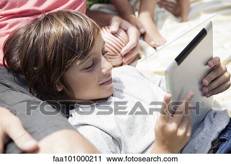 Boy using digital tablet outdoors View Large Photo Image Stock Image - Boy using digital tablet outdoors. Fotosearch