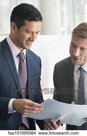 Business associates discussing document together View Large Photo Image Picture - Business associates discussing document together. Fotosearch