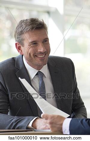 Businessman discussing paperwork with client View Large Photo Image Stock Image - Businessman discussing paperwork with client. Fotosearch