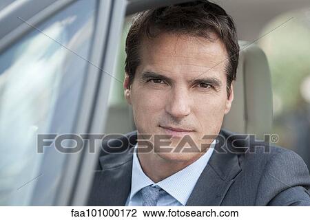 Stock Image - "Businessman driving car, portrait". Fotosearch