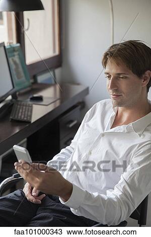 Businessman holding smartphone in office View Large Photo Image Stock Image - Businessman holding smartphone in office. Fotosearch