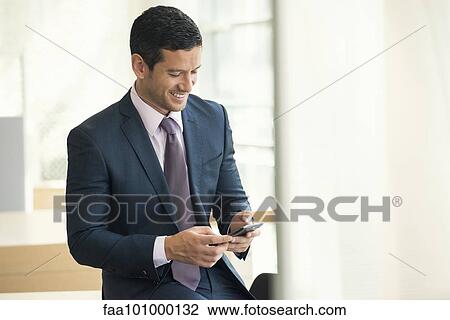 Businessman looking at smartphone and smiling View Large Photo Image Stock Image - Businessman looking at smartphone and smiling. Fotosearch
