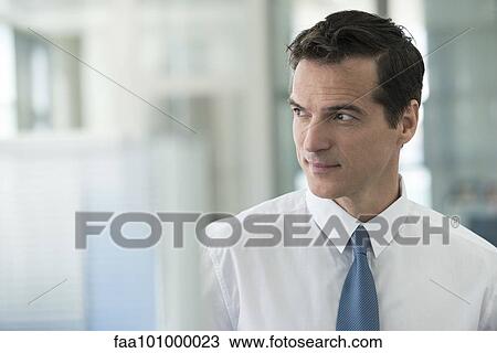 Stock Image - "Businessman looking away in thought, portrait". Fotosearch