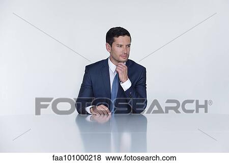 "Businessman seated at table, looking away in thought" View Large Photo Image Stock Photo - "Businessman seated at table, looking away in thought". Fotosearch