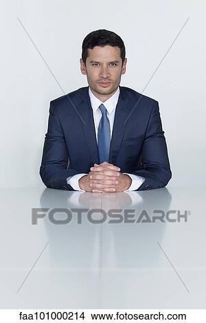 "Businessman sitting at conference table with clasped hands, portrait" View Large Photo Image Picture - "Businessman sitting at conference table with clasped hands, portrait". Fotosearch