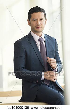 Stock Photography - "Businessman sitting on edge of table, portrait". Fotosearch