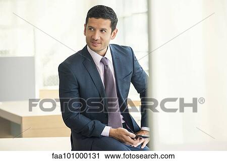 "Businessman sitting with smartphone in hand, looking away and smiling" View Large Photo Image Stock Image - "Businessman sitting with smartphone in hand, looking away and smiling". Fotosearch