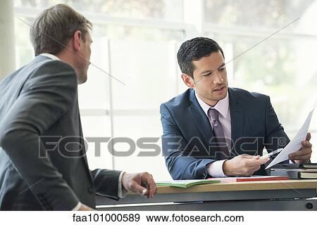 Stock Photo - Businessmen discussing contract in meeting. Fotosearch