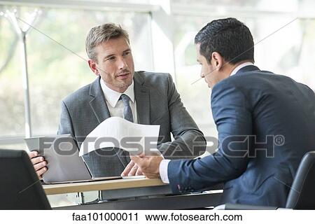 Stock Image - Businessmen negotiating in meeting. Fotosearch