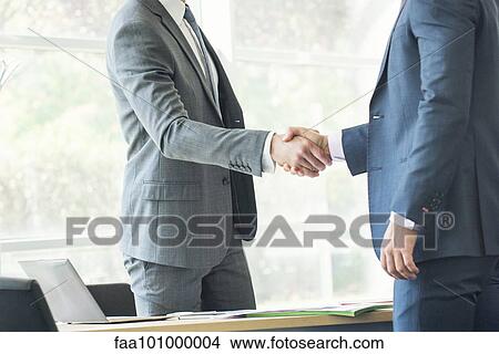 Businessmen shaking hands in office View Large Photo Image Picture - Businessmen shaking hands in office. Fotosearch