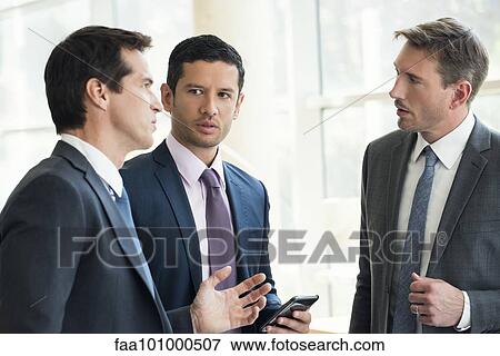 Businessmen standing together having serious discussion View Large Photo Image Stock Photo - Businessmen standing together having serious discussion. Fotosearch