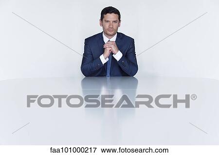 "Confident businessman seated at table, portrait" View Large Photo Image Stock Photo - "Confident businessman seated at table, portrait". Fotosearch