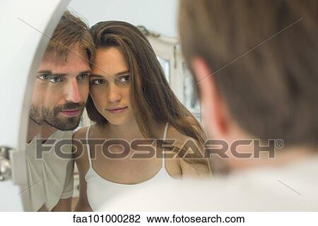 Stock Image - Couple cheek to cheek looking into mirror together. Fotosearch