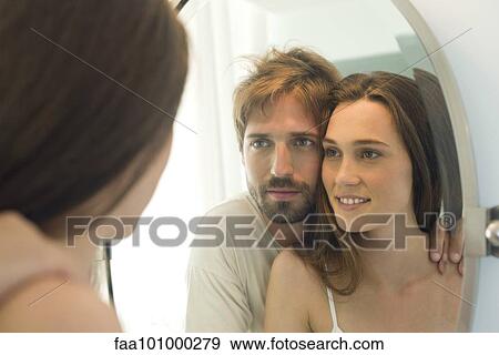 Stock Photo - Couple looking in bathroom mirror together. Fotosearch