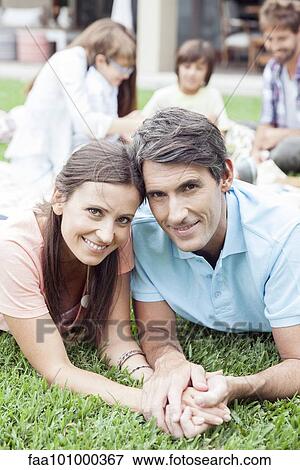 Stock Photo - "Couple lying side by side holding hands, portrait". Fotosearch