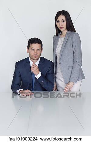 Picture - "Executive seated beside standing assistant, portrait". Fotosearch