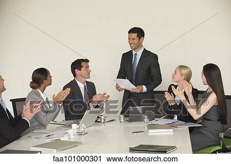 Stock Image - Executve being applauded by colleagues in meeting. Fotosearch