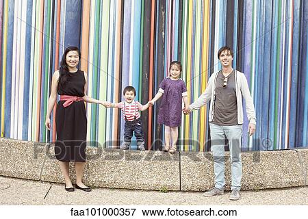 "Family holding hands together in front of colorful striped sculpture, La Defense, Paris, France" View Large Photo Image Stock Photo - "Family holding hands together in front of colorful striped sculpture, La Defense, Paris, France". Fotosearch