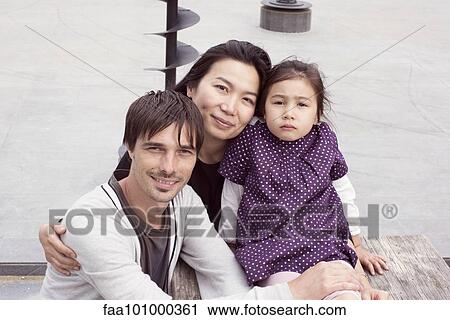 Stock Image - "Family sitting together outdoors, portrait". Fotosearch