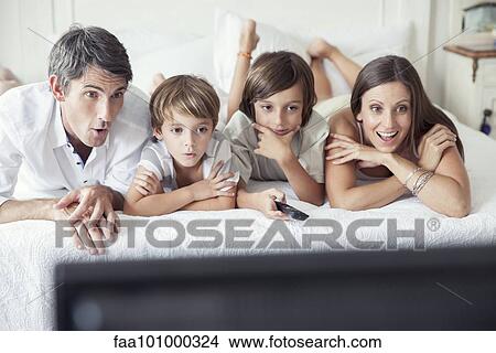 "Family watching TV on bed, portrait" View Large Photo Image Picture - "Family watching TV on bed, portrait". Fotosearch
