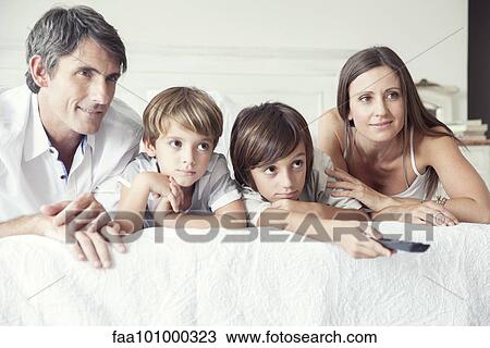 "Family watching TV on bed, portrait" View Large Photo Image Stock Image - "Family watching TV on bed, portrait". Fotosearch