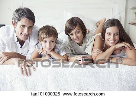 "Family watching TV on bed, portrait" View Large Photo Image Stock Photography - "Family watching TV on bed, portrait". Fotosearch