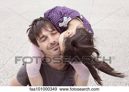 Stock Photo - "Little girl riding on father's shoulders, kissing his cheek". Fotosearch
