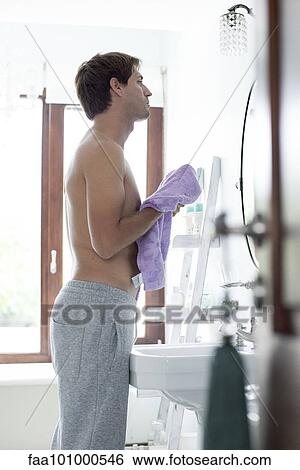 Man in bathroom drying off with towel View Large Photo Image Stock Photograph - Man in bathroom drying off with towel. Fotosearch